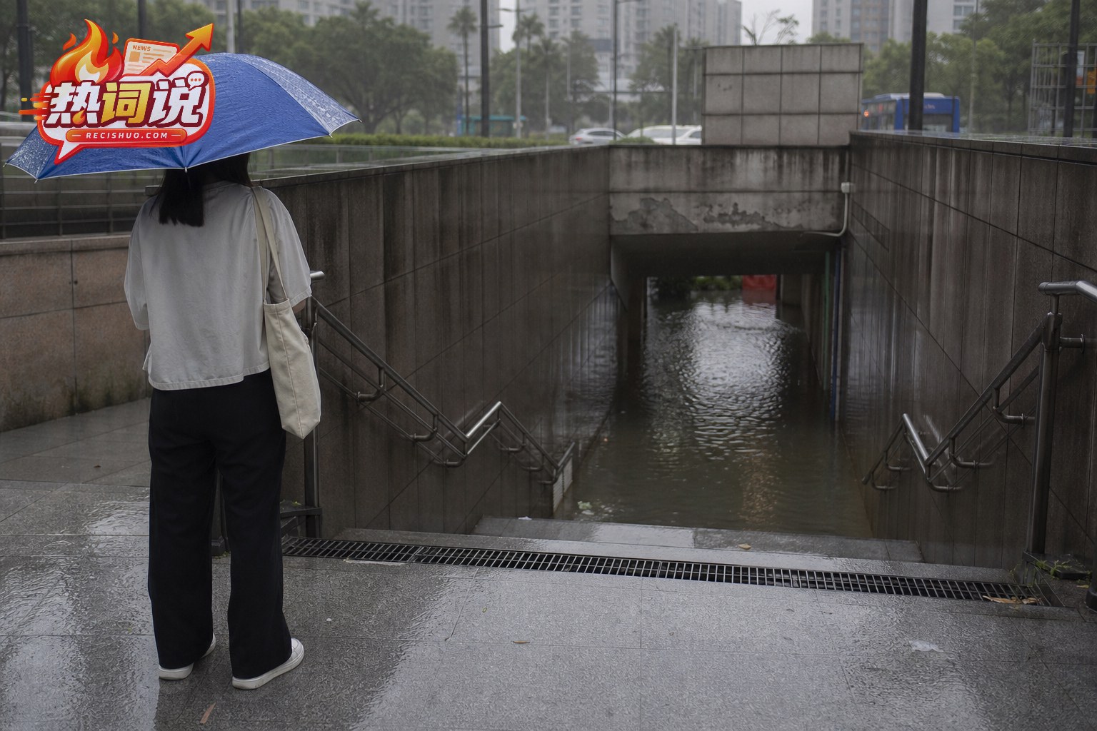上海一处积水的地下通道入口,行人停在安全位置观察并准备绕行