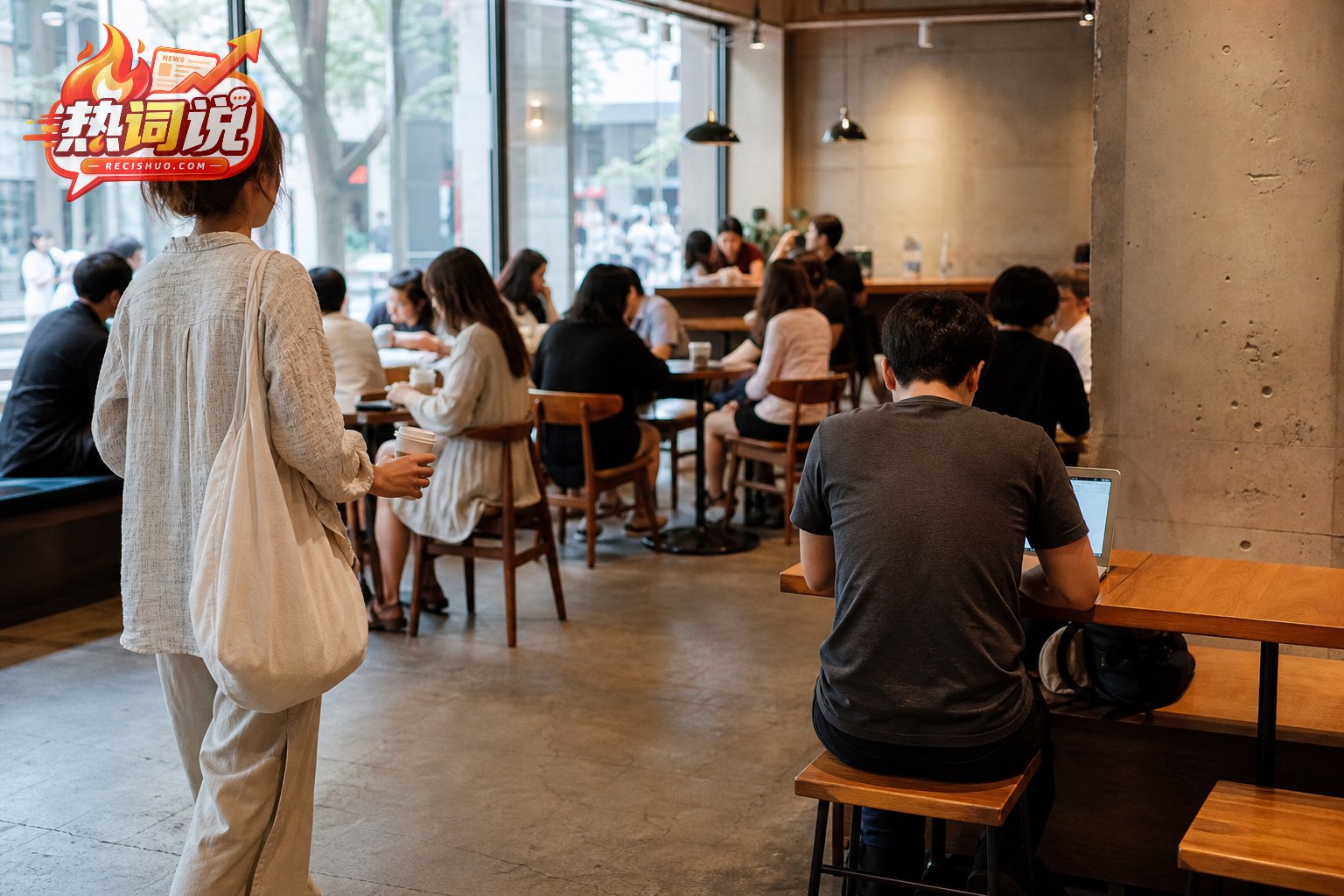 繁忙咖啡店内,持杯顾客寻找座位,一名使用电脑的客人坐在桌前