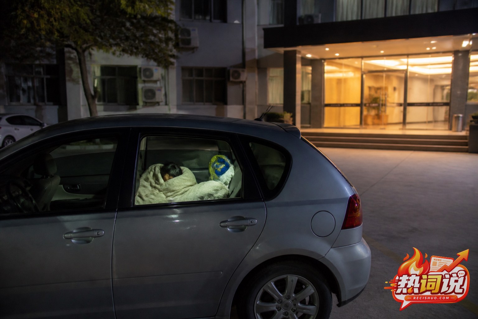 夜间停在住宿场所外的汽车内有旅客盖着毯子休息