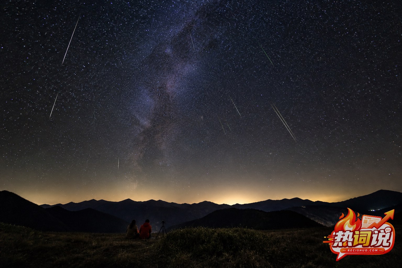 英仙座流星雨划过夏夜星空,两名观测者在山地草坡守候