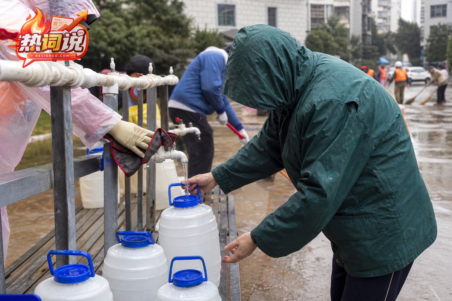 洪涝灾后居民在社区临时供水点用带盖容器接取饮用水