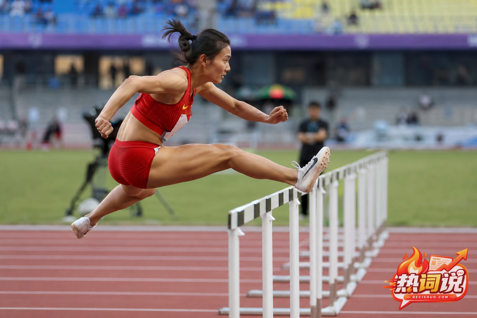 女子100米栏运动员在比赛中完成过栏动作的侧面特写