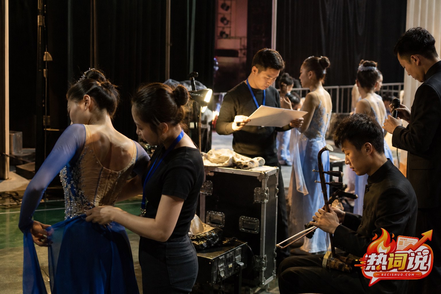 文艺汇演后台演员整理服装、乐手检查乐器和工作人员核对流程的候场场景
