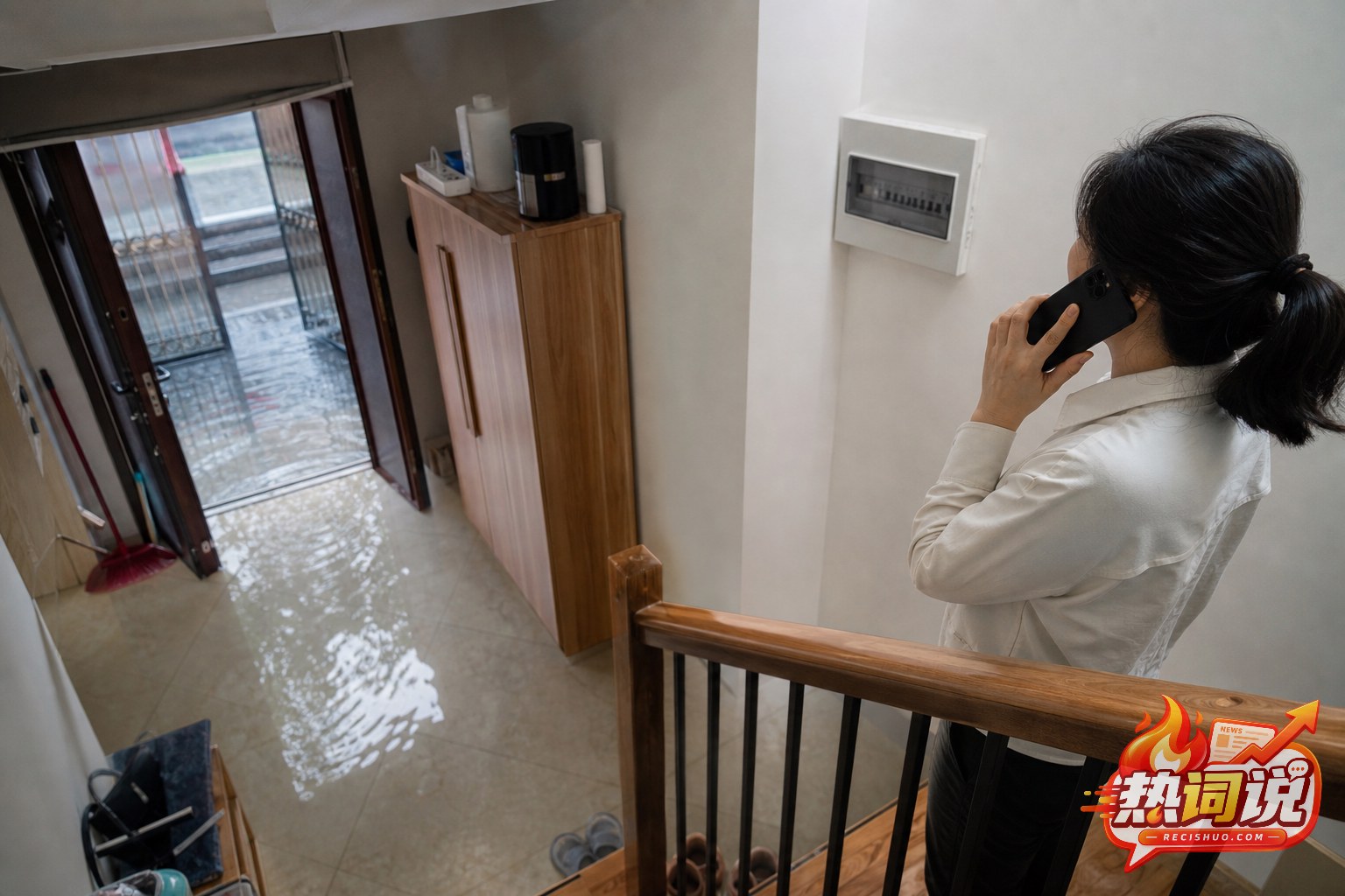 住宅入口进水后,住户站在干燥楼梯高处联系专业人员处理