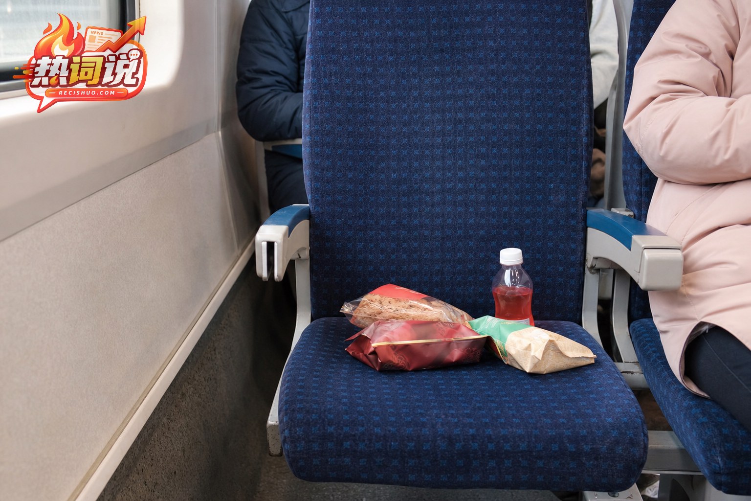 列车空闲硬座上放着数包零食和一瓶饮料的近景