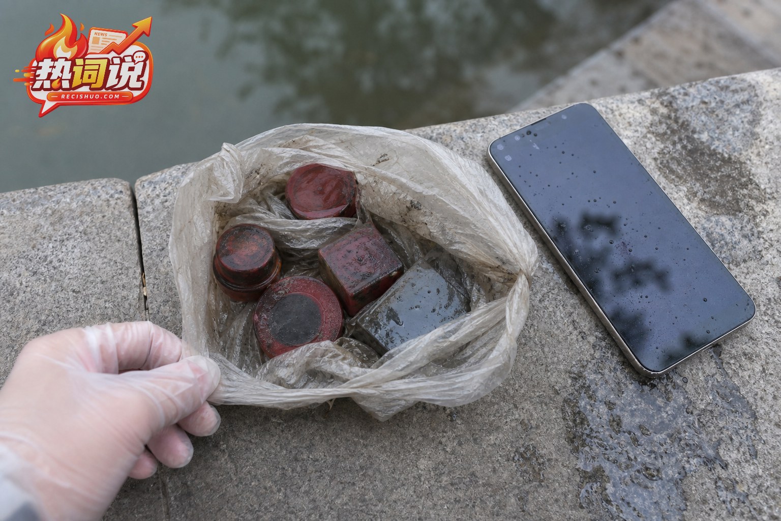 河岸石台上保持原状的湿塑料袋、印章状物体与用于记录现场的手机