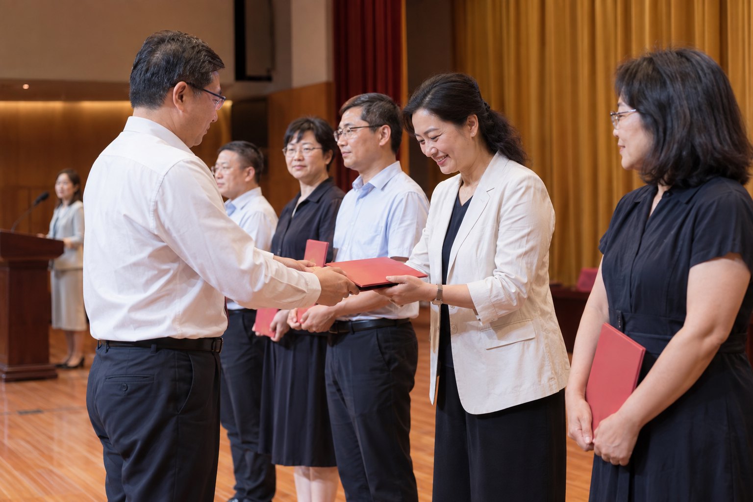 高校礼堂内多名教师依次接受表彰的纪实场景