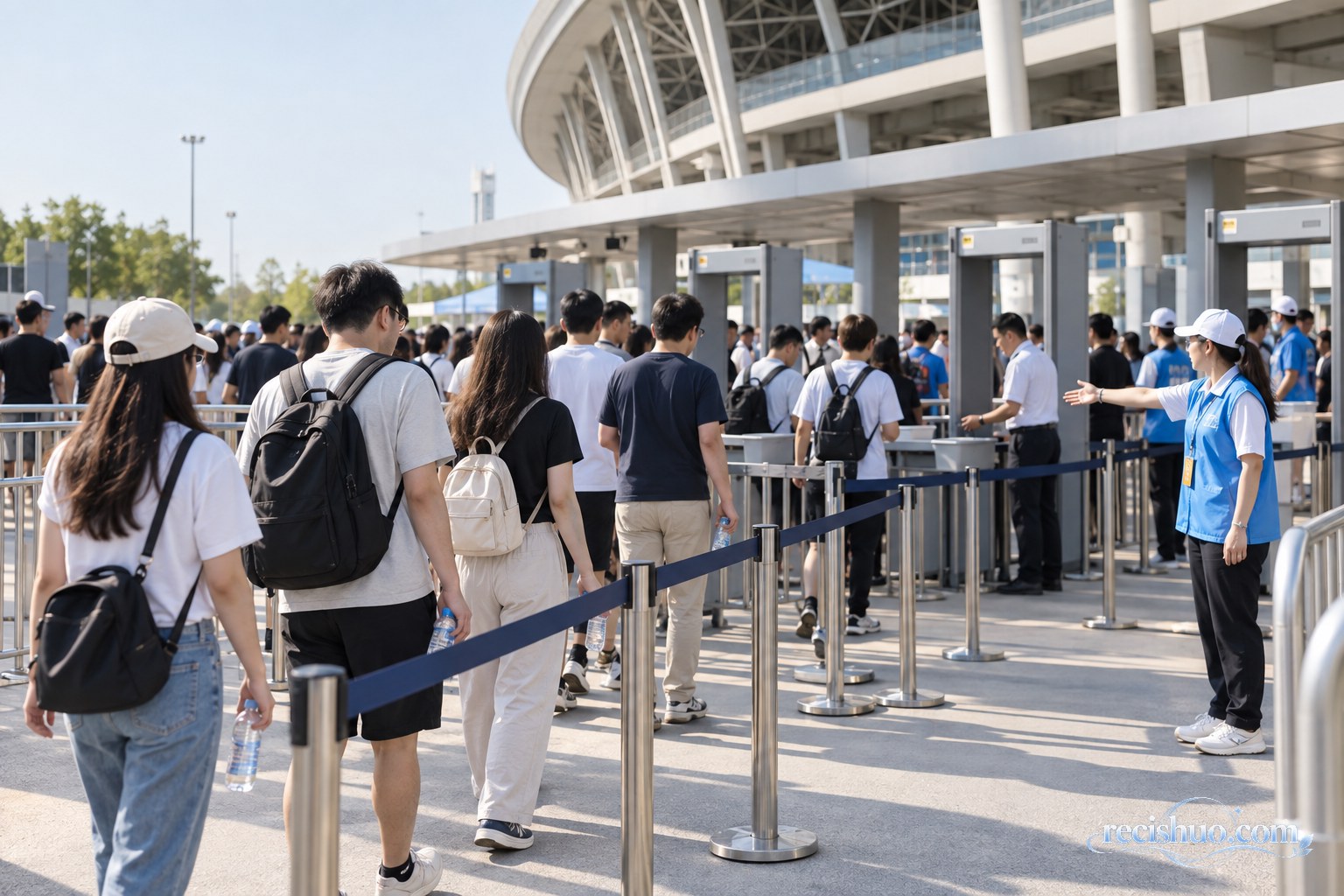 大型体育场入口处，观众在工作人员引导下有序接受安检