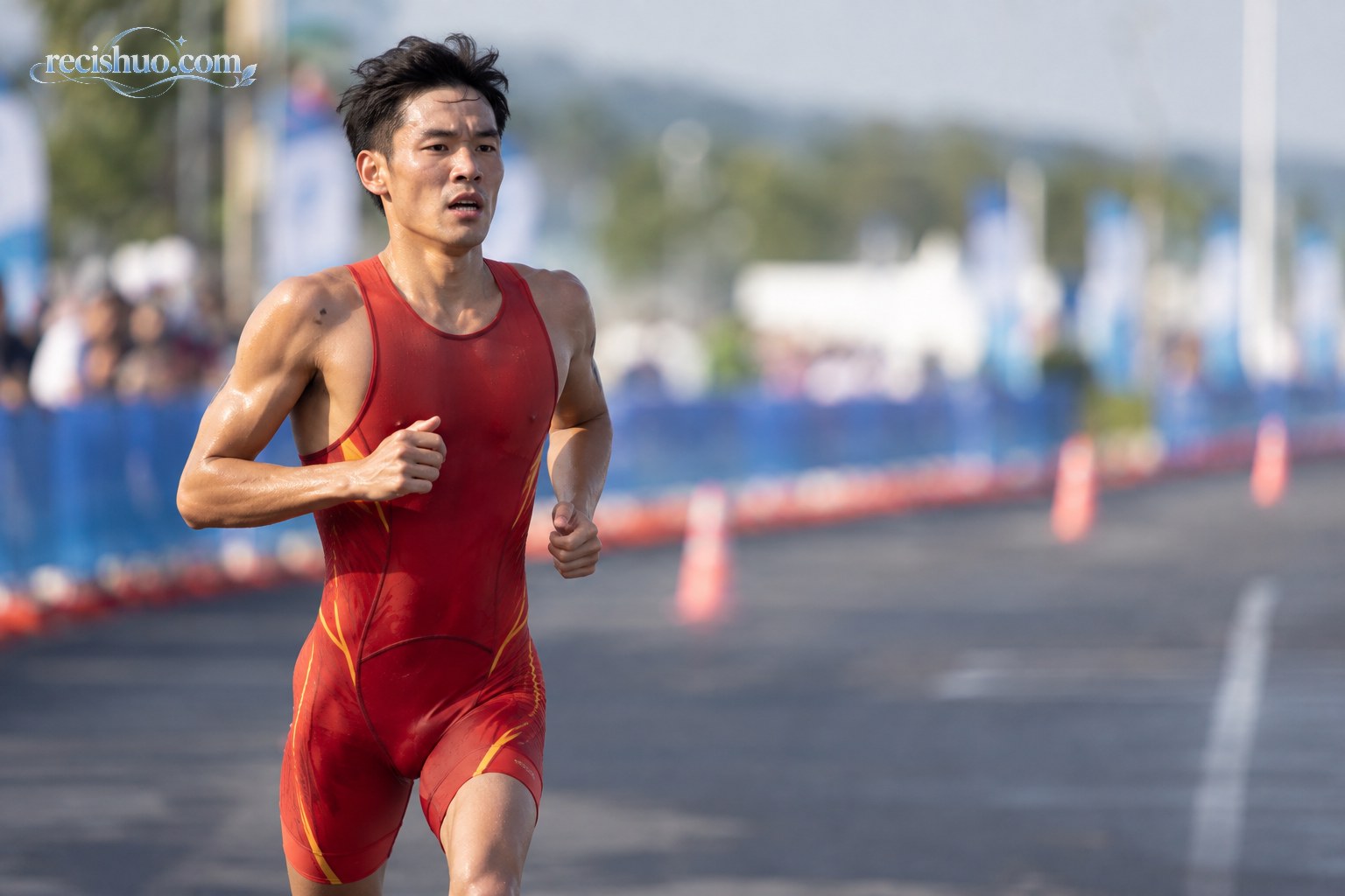 身穿红色比赛服的中国男子铁人三项运动员在公路赛段奋力奔跑