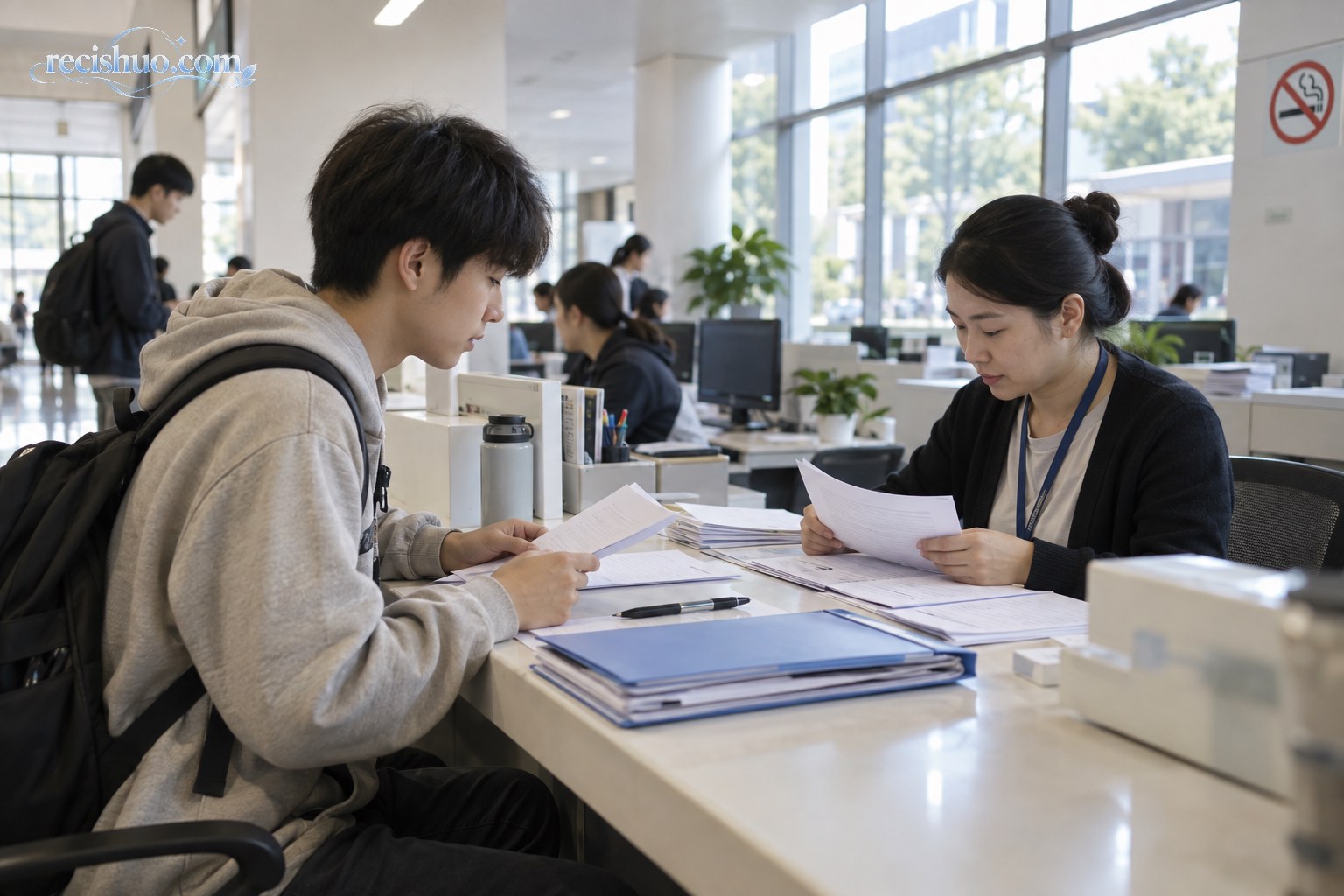 大学生在高校学生事务窗口提交学费减免申请材料,工作人员正在核对文件