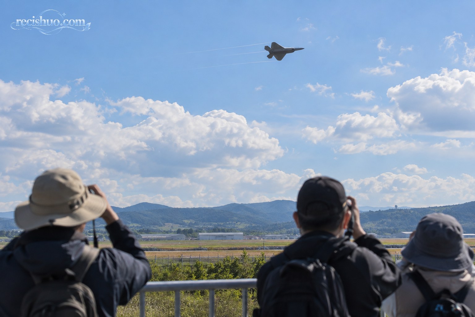 航空爱好者在公共观景区远距离观看战斗机飞行
