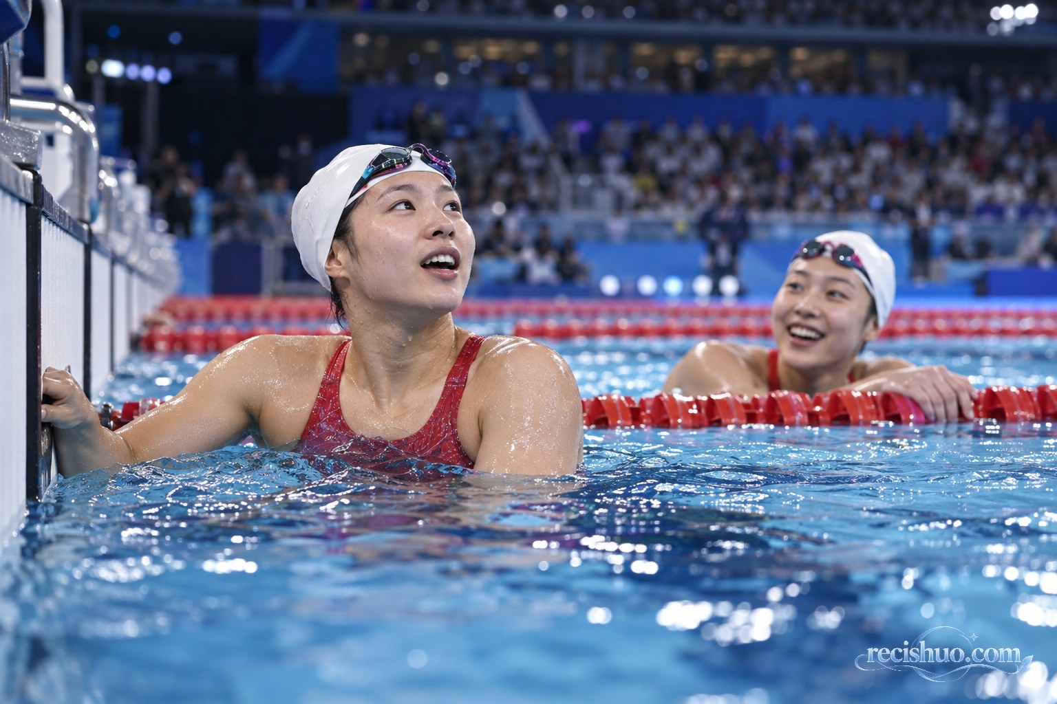 两名女子游泳运动员在比赛结束后于泳池终点交流庆祝