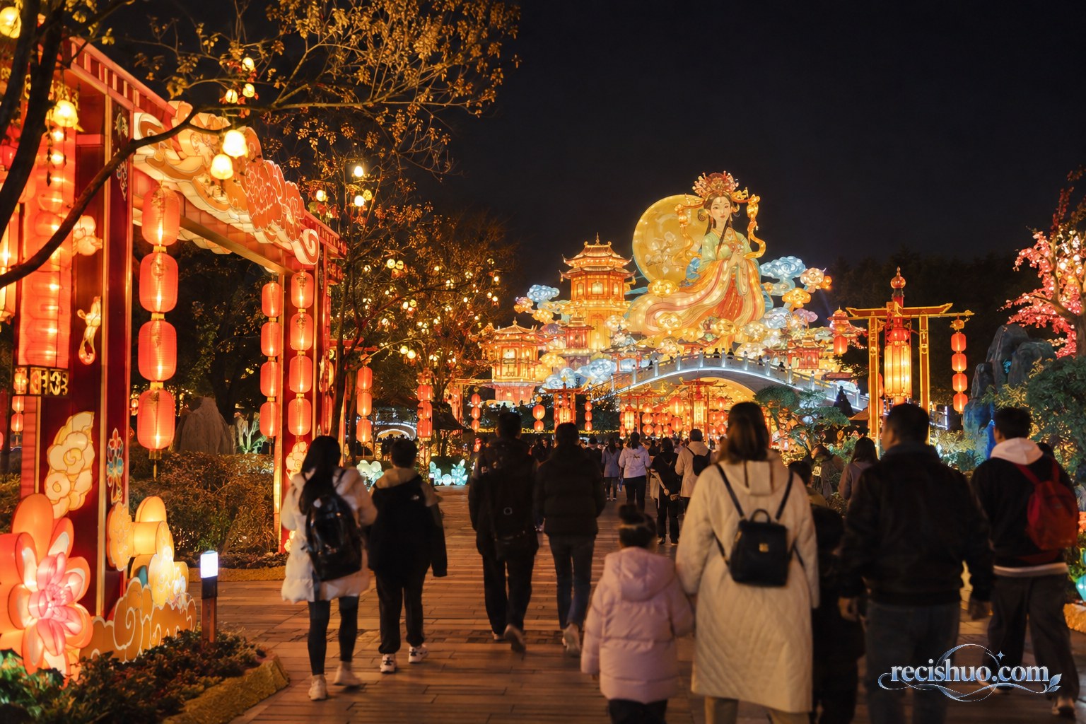 夜色中游客沿公园步道欣赏暖金与红色大型彩灯