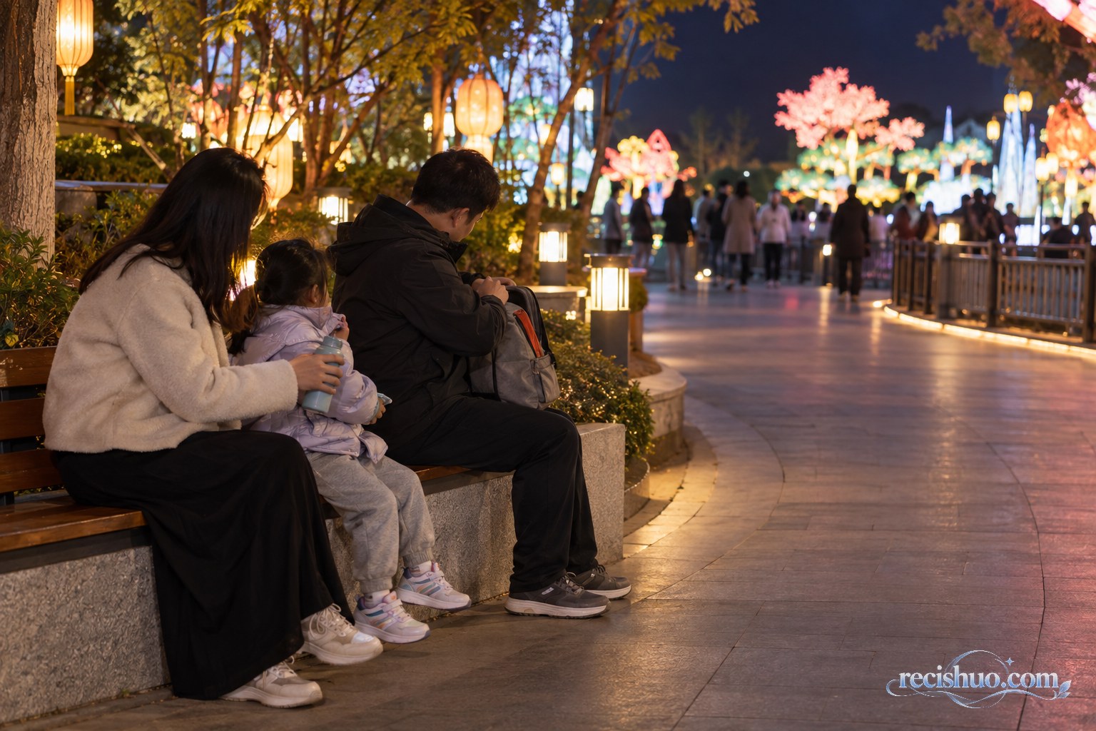 带孩子的家庭在灯会休息区补水并整理随身背包