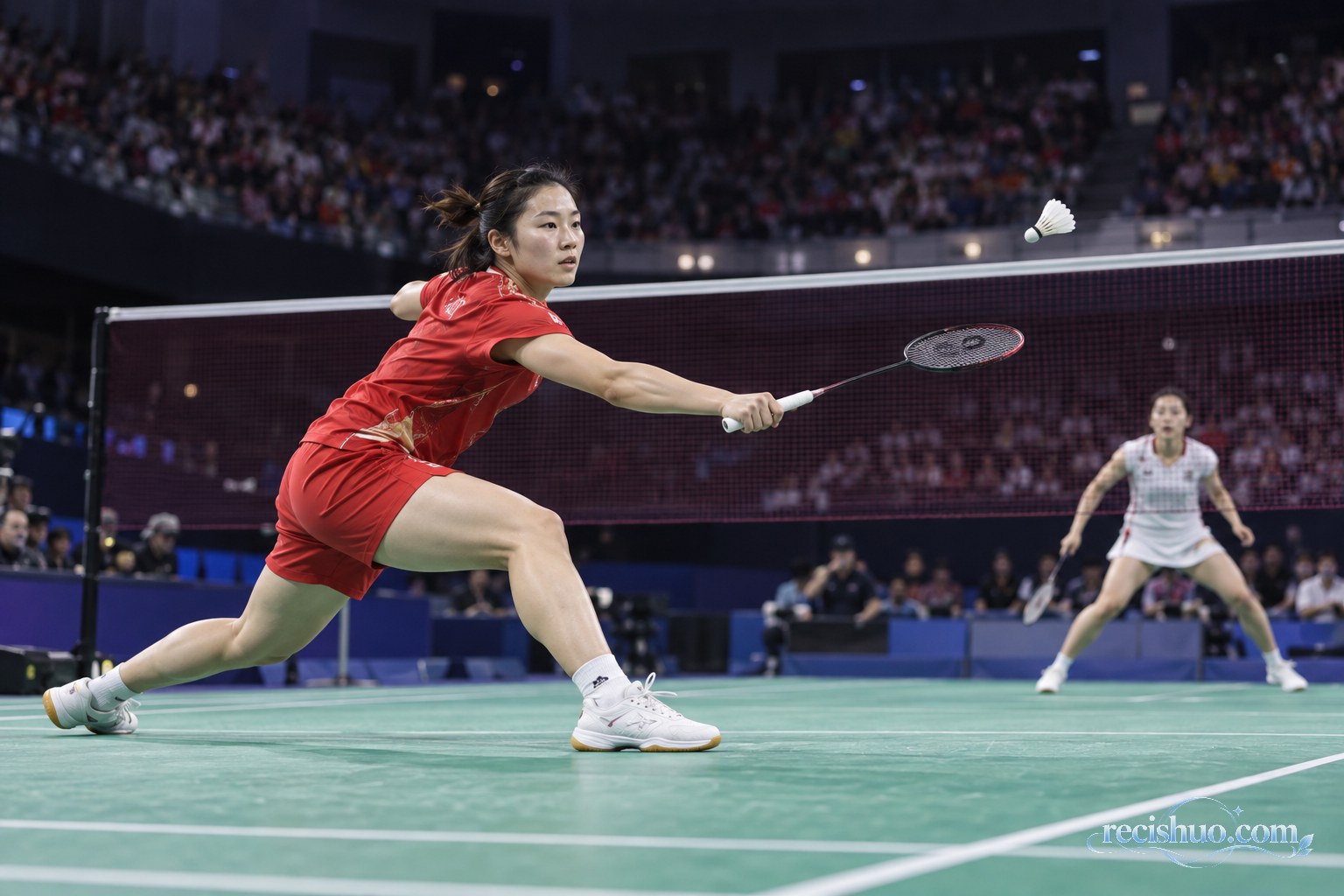 中国女羽运动员在室内赛场前场伸拍回击羽毛球