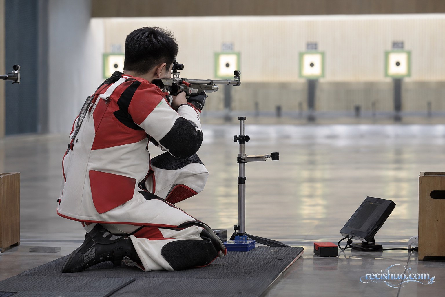 男子射击运动员在室内靶位完成步枪跪姿瞄准
