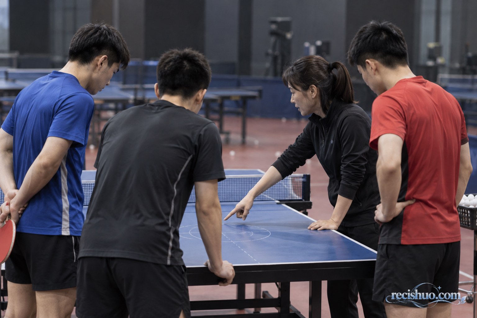 教练与三名男子乒乓球运动员围绕球台复盘技战术的示意画面