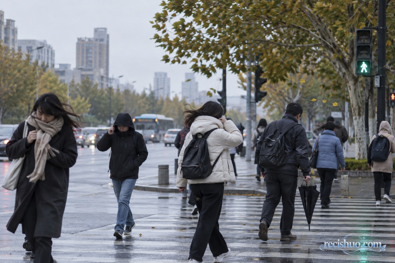 阴雨降温天气中,穿着外套的行人经过城市街口