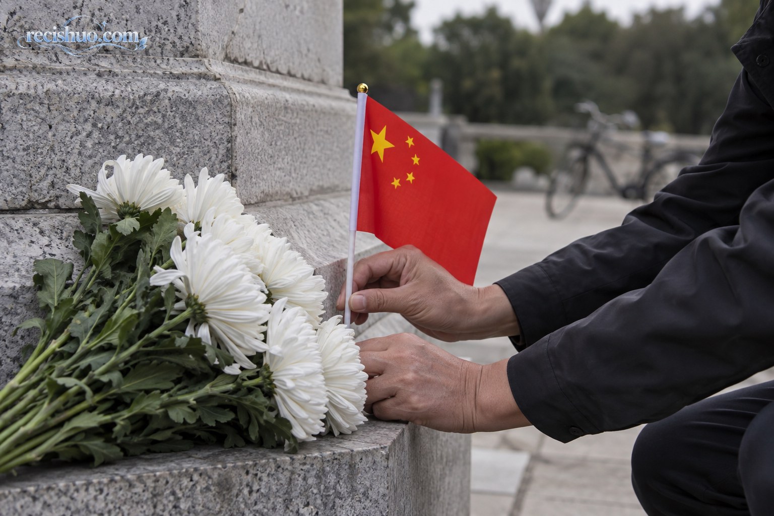 一名参观者在烈士纪念碑基座旁郑重放置国旗和白色菊花