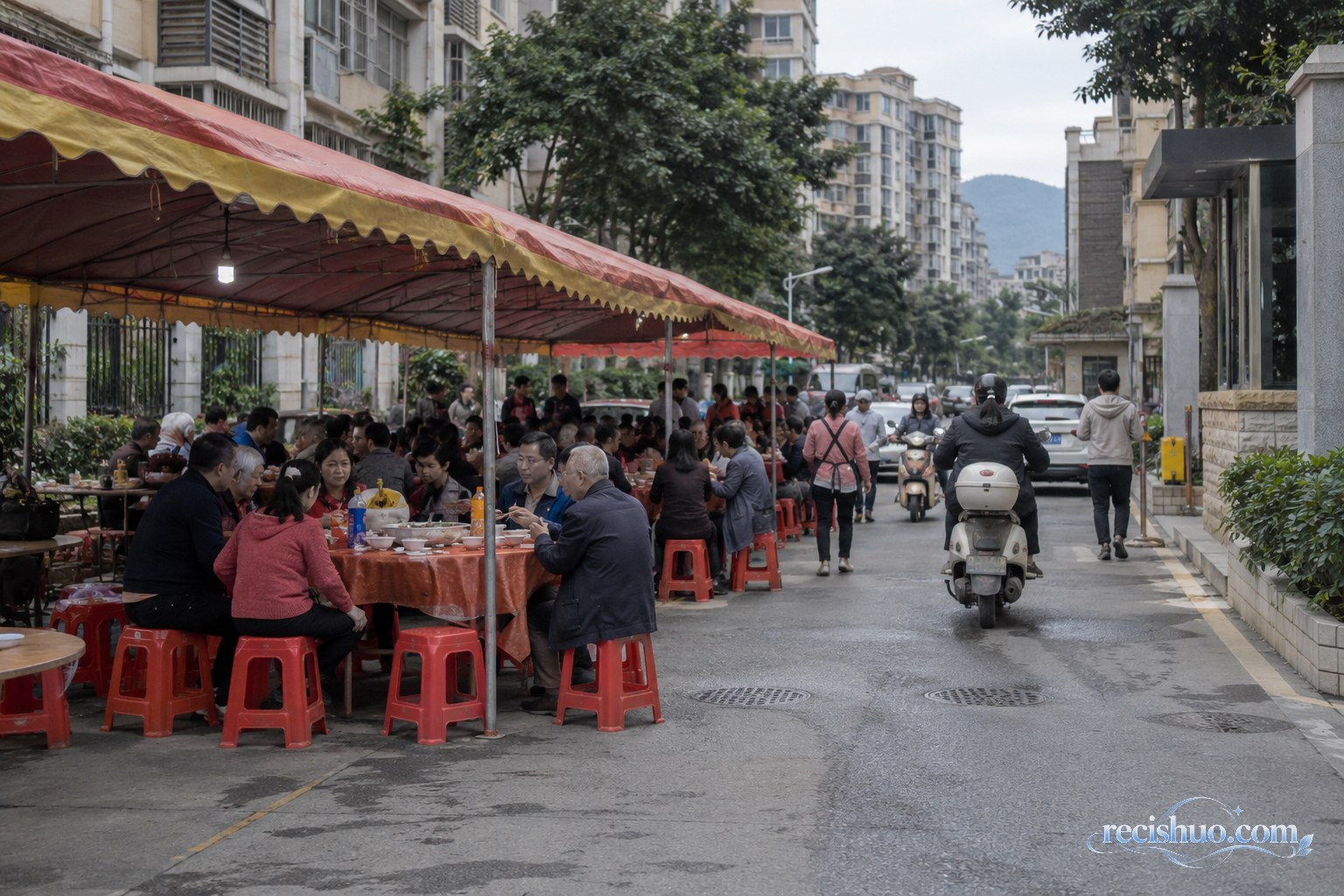 住宅小区门口道路一侧搭设宴席棚,居民用餐时仍有行人和电动车通行