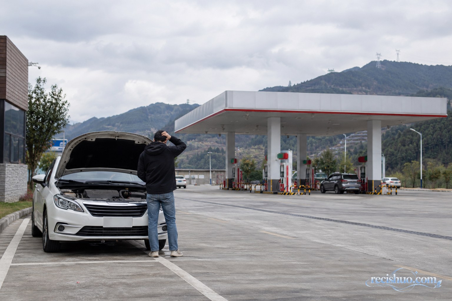 轿车因故停在高速服务区内,车主站在车旁,远处可见加油设施