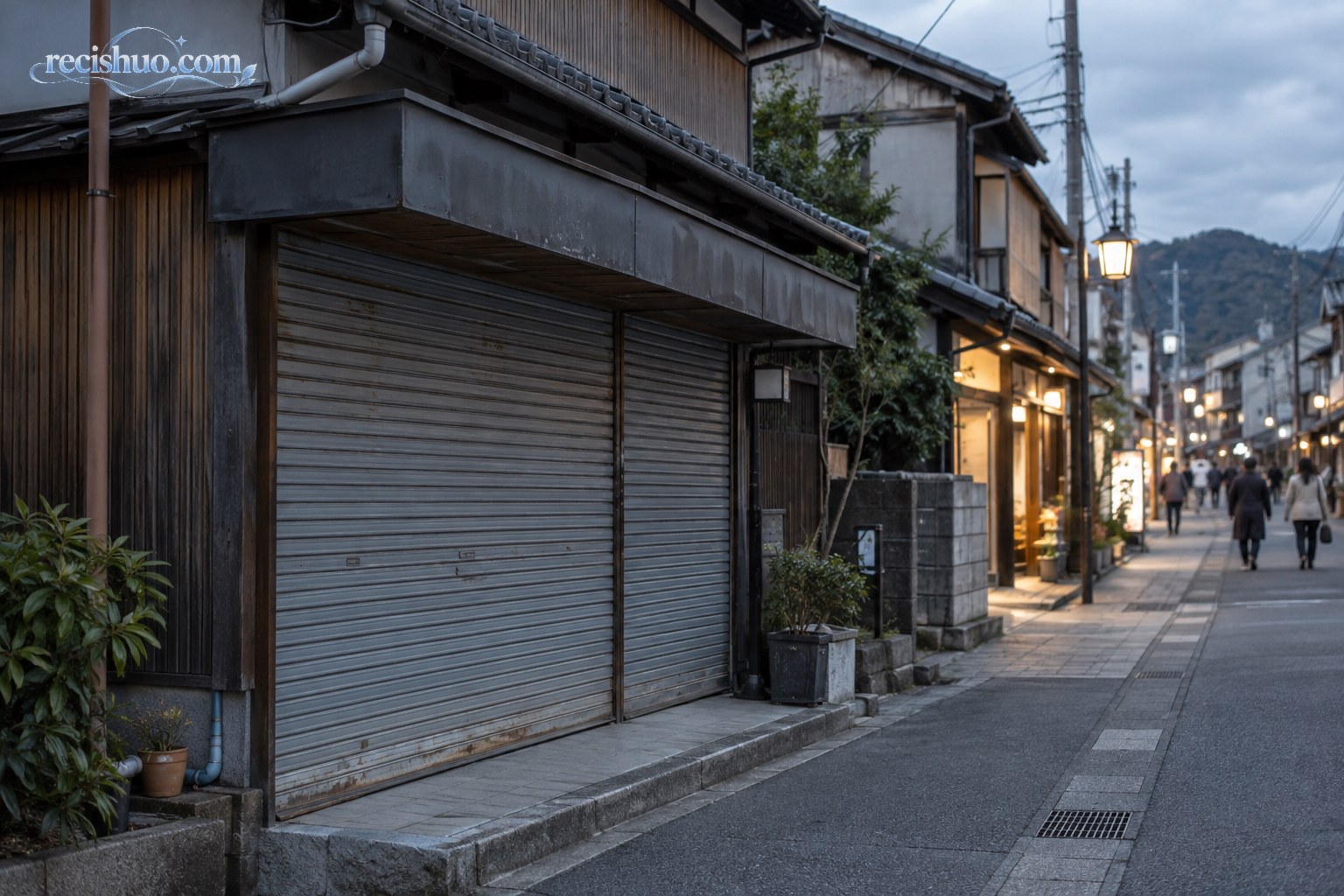 日本传统商业街上一家卷帘门紧闭的店铺，周边仍有少量行人与营业门店