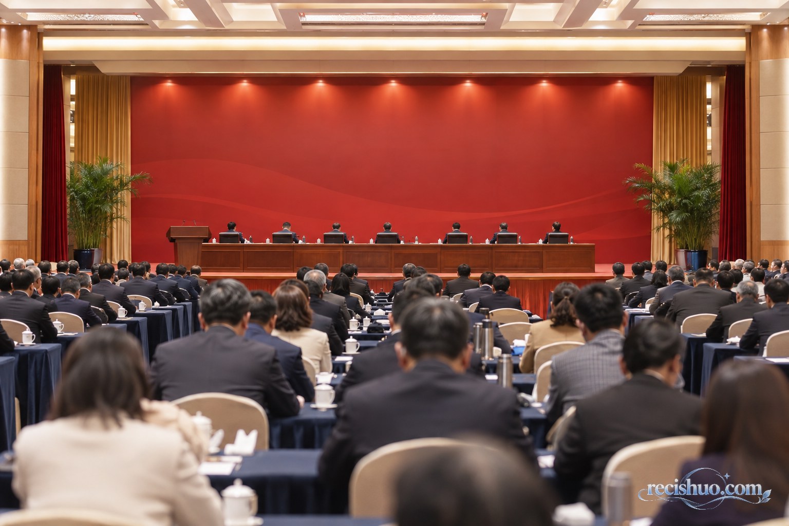 庄重的现代大会会场内参会人员面向红色背景主席台