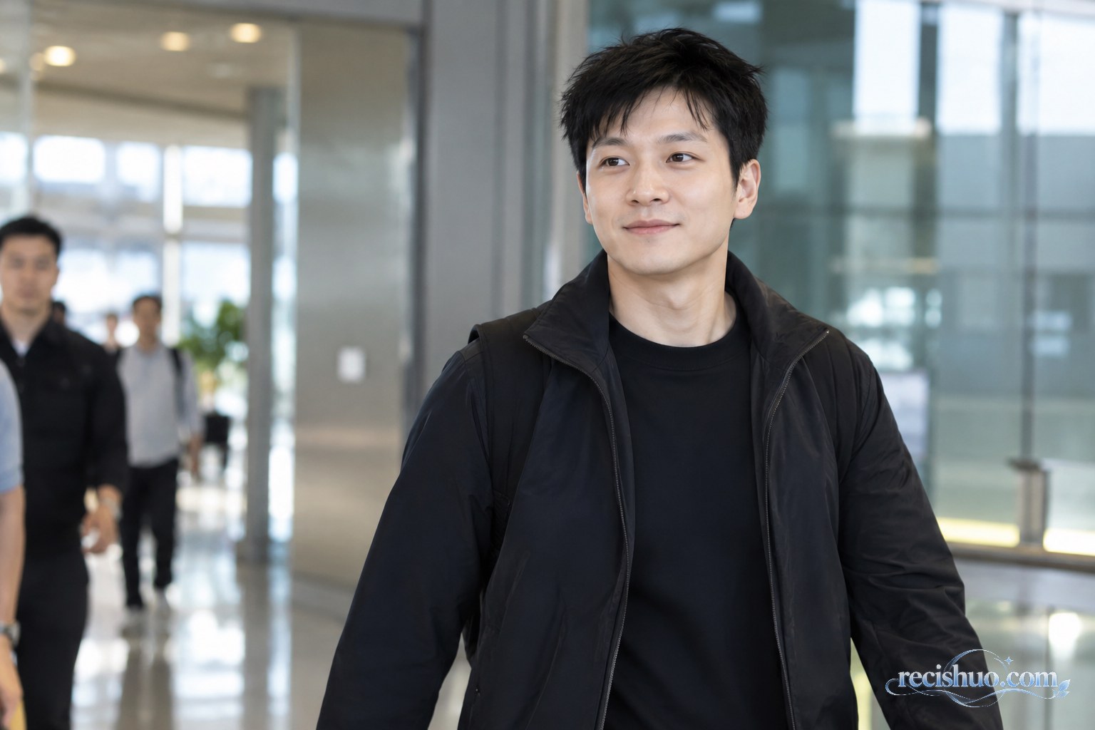 身穿深色夹克的乒乓球运动员轻松走过明亮的室内通道