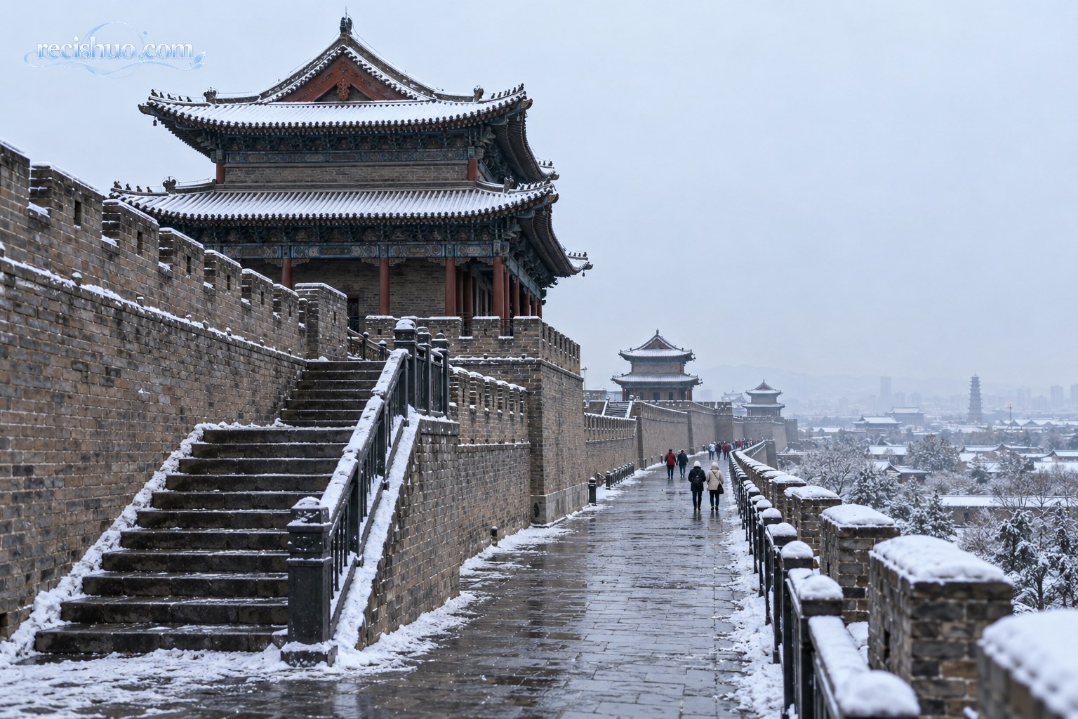 薄雪勾勒大同古城墙与城楼轮廓,石阶和步道路面仍显湿滑