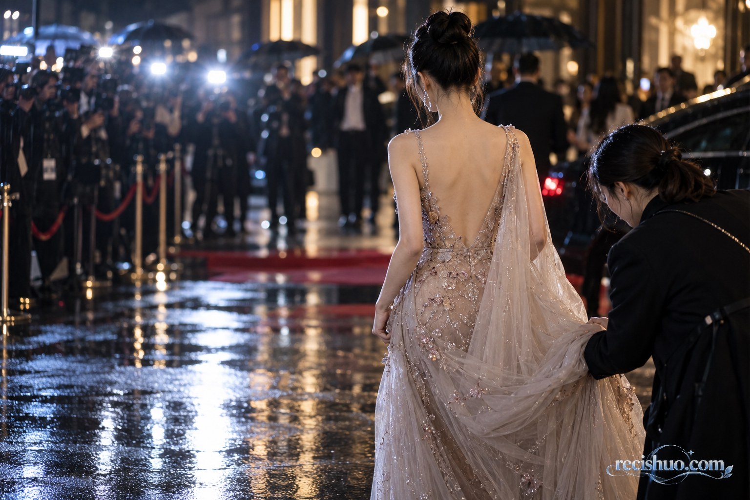 雨夜时尚活动入口,一名工作人员为身着礼服的女性嘉宾整理衣摆